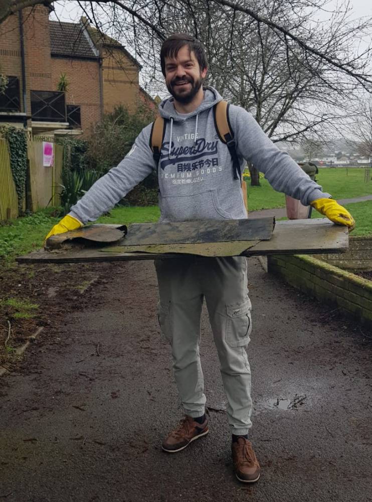 A volunteer carries large items of refuse to the collection point